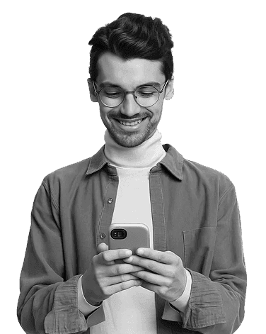 A smiling man wearing glasses and a turtleneck, looking at his smartphone.